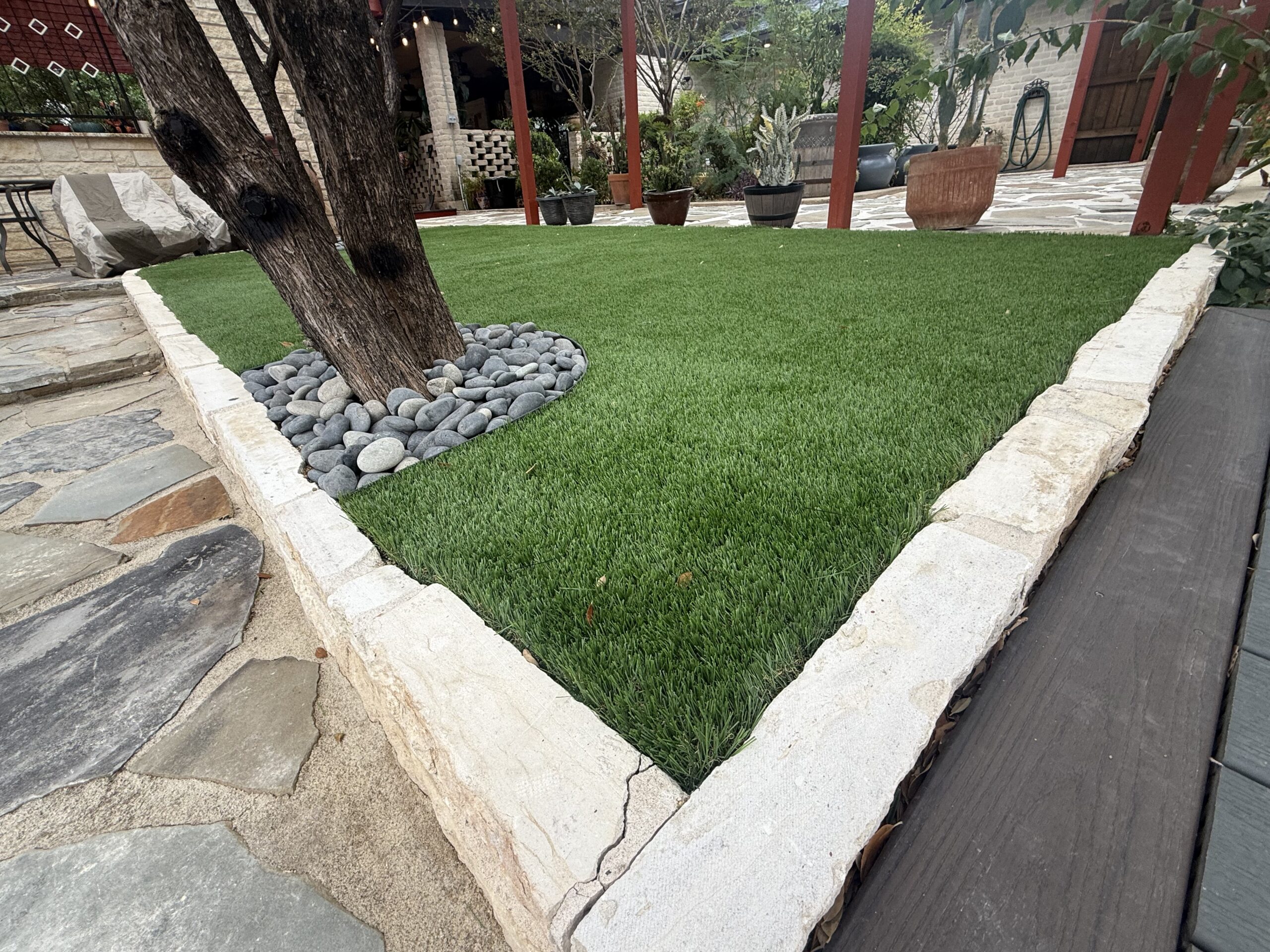 Landscaping in Boerne, TX Limestone landscape border edging a lawn and tree bed