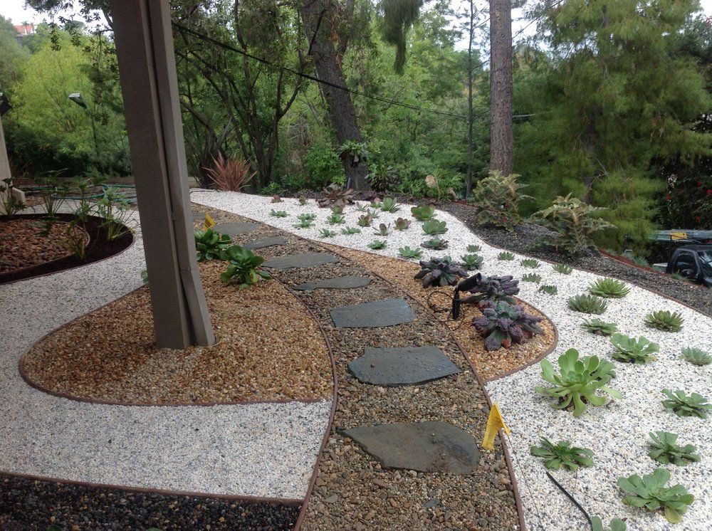 Xeriscape with decorative rock, stepping stones and drought-tolerant plants under shade trees