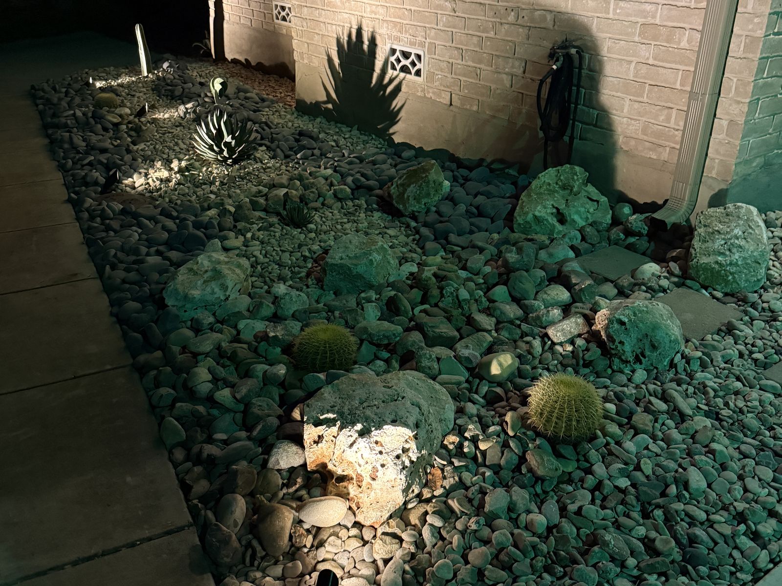 Xeriscape rock bed along a walkway with low-voltage accent lights at night