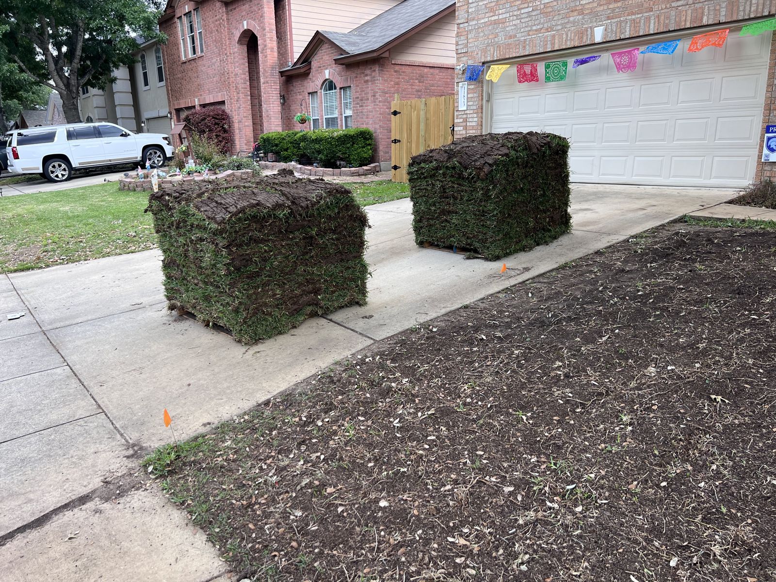 Before: front yard stripped to bare soil with sod pallets on the driveway