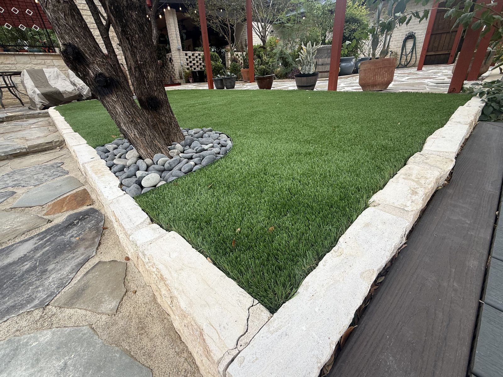 River-rock rings around tree trunks in an artificial turf yard